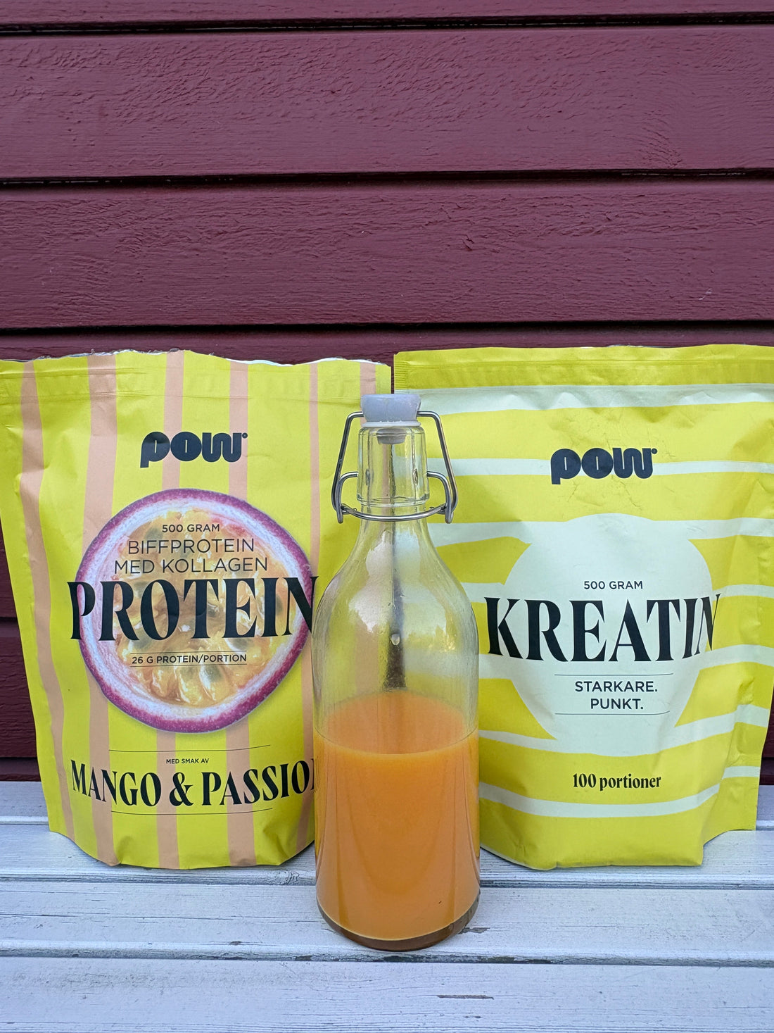 Ingefärashot i glasflaska framför POW biffprotein med kollagen mango & passion och POW kreatin – proteinrik morgonshot