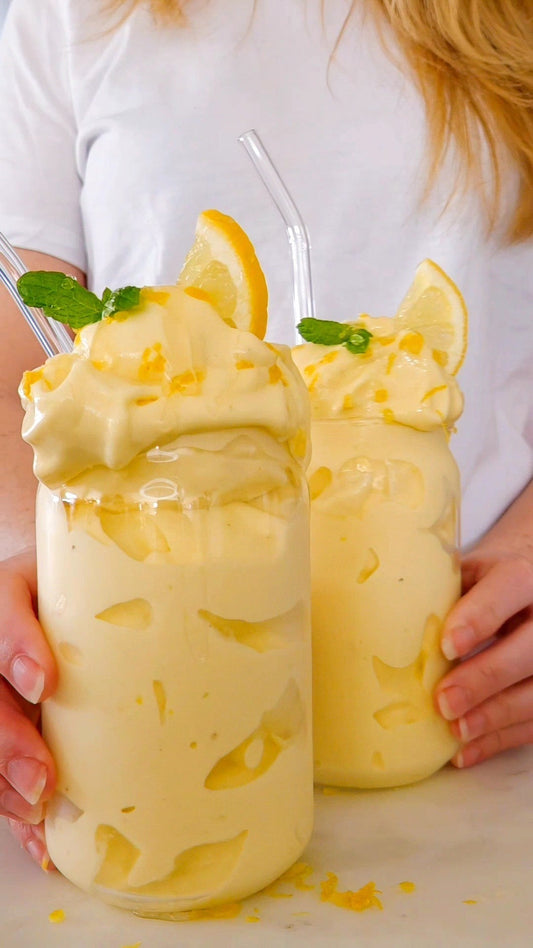  Krämig citrongul nicecream i skål, toppad med rivet citronskal och honung – gjord med clear whey protein från POW.