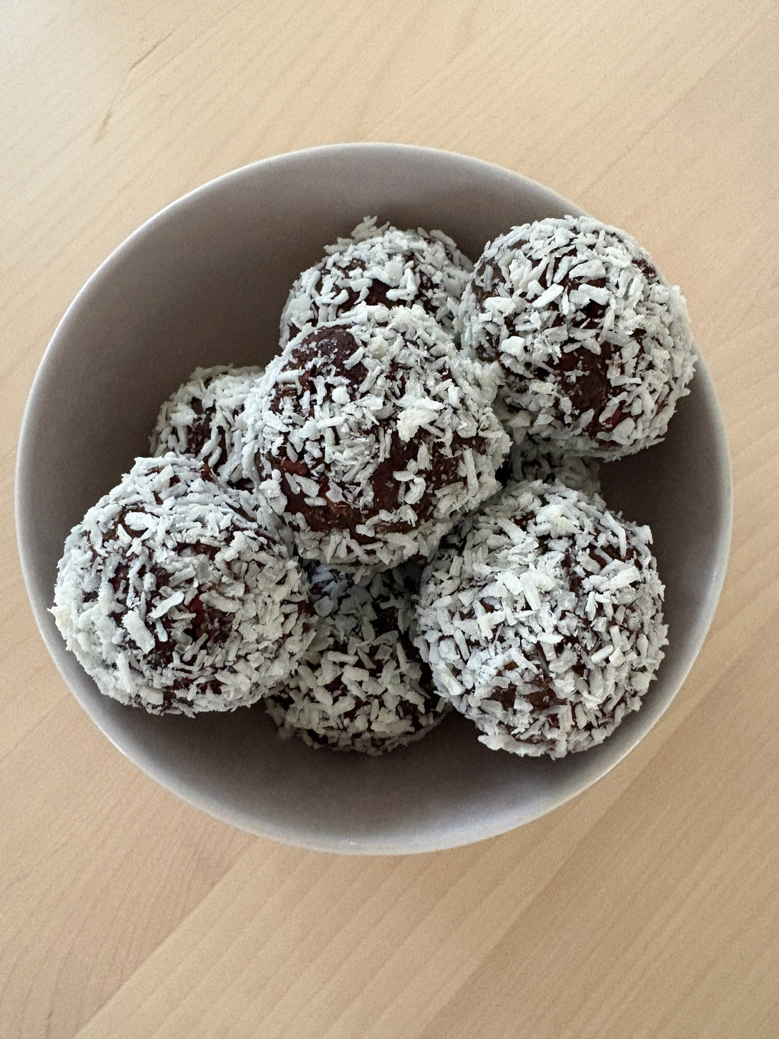 Mintchokladbollar med protein rullade i kokos i en skål, gjorda på dadlar, valnötter och POW kaseinprotein päron & mintchoklad
