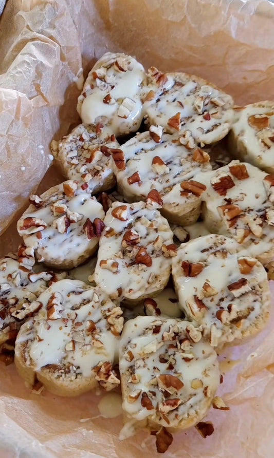 Skivade no-bake kanelbullar med vassleprotein, toppade med smält vit choklad och hackade pecanötter