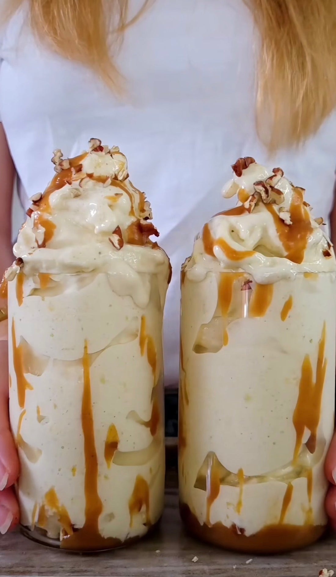 Syrlig proteinnicecream med mango, banan och zucchini toppad med salt kolasås och hackade pecannötter i två glas