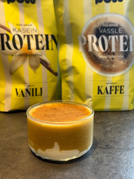 Glas med pumpkin spice latte med proteinskum och kanel framför en förpackning POW vaniljkasein