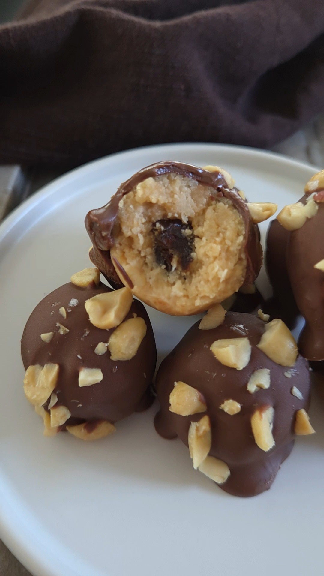 Chokladdoppade proteinbollar med dadelgömma och hackade jordnötter på ett fat