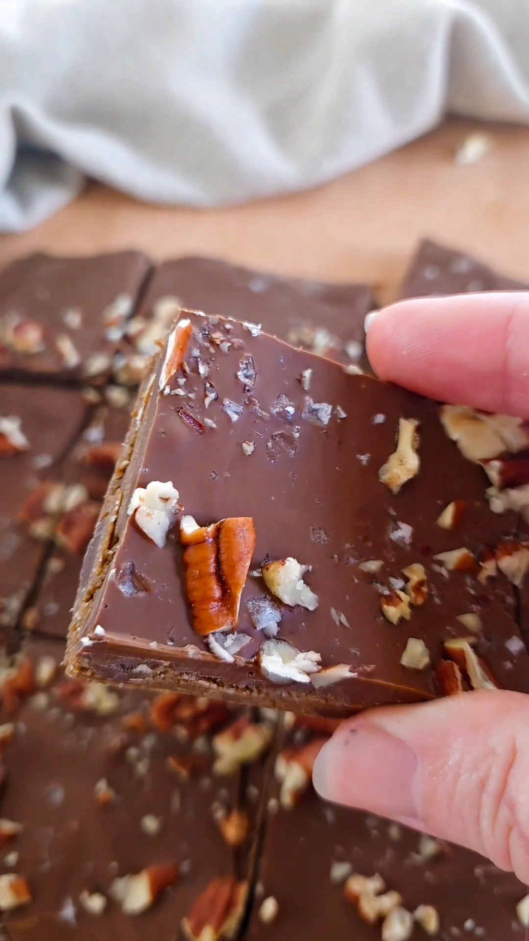 Veganska triple chocolate bark-bitar med smält choklad, pecannötter och flingsalt på bakplåtspapper.